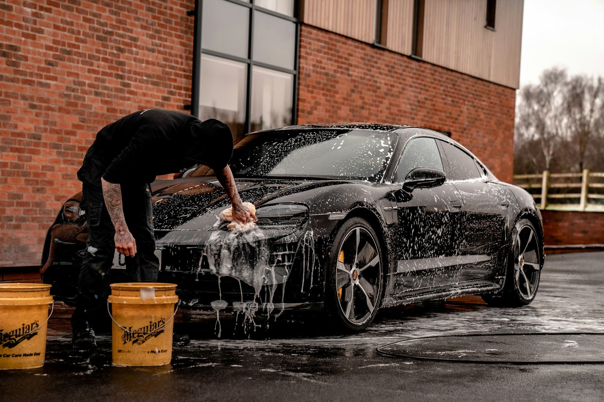 Detailer hand-washing a black Porsche
